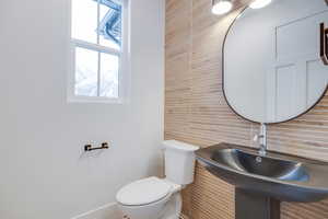 Bathroom with tile walls, sink, tasteful backsplash, and toilet