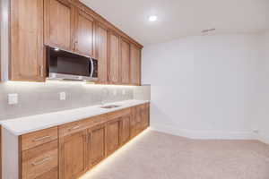 Kitchen with light colored carpet, sink, and decorative backsplash