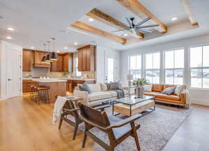 Living room with ceiling fan, a tray ceiling, a textured ceiling, beam ceiling, and light hardwood / wood-style flooring