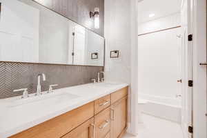 Bathroom featuring tile walls, backsplash, tiled shower / bath combo, vanity, and tile patterned floors