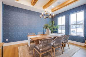 Dining area with an inviting chandelier, hardwood / wood-style flooring, beamed ceiling, and a healthy amount of sunlight