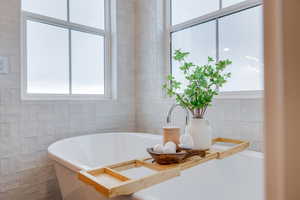 Bathroom featuring a washtub and tile walls