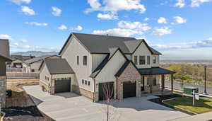 Modern farmhouse featuring brick siding, concrete driveway, a shingled roof, covered porch, and a standing seam roof