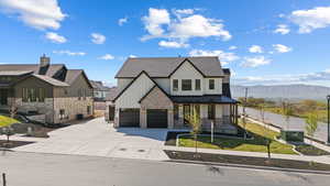 View of front of house with driveway, board and batten siding, fence, a porch, and a standing seam roof