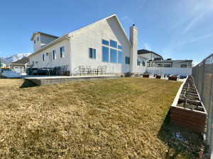 Rear view of property with a grassy area, garden boxes & a patio/deck