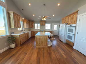 Kitchen with a center island, sink, lofted ceiling, and white appliances