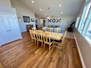 Dining area with hardwood flooring, high vaulted ceiling, ceiling fan, and a wood stove