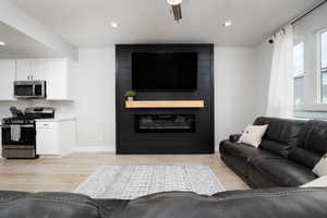 Living room featuring ceiling fan, a large fireplace, and light wood-type flooring