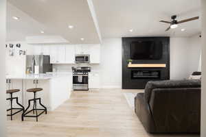 Kitchen with stainless steel appliances, a breakfast bar, white cabinets, and a fireplace