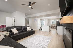 Living room featuring sink, ceiling fan with notable chandelier, and light wood-type flooring