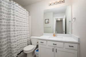 Bathroom with vanity, curtained shower, and toilet