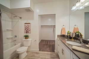 Full bathroom with vanity, hardwood / wood-style floors, shower / bathtub combination, and toilet