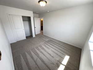 Unfurnished bedroom featuring a closet, carpet floors, baseboards, and a textured ceiling