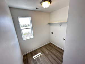 Washroom featuring washer hookup, baseboards, wood finished floors, electric dryer hookup, and a textured ceiling
