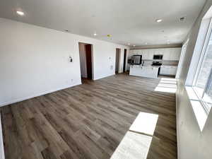 Unfurnished living room with a sink, light wood finished floors, recessed lighting, and baseboards