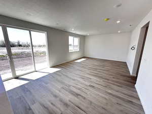 Spare room with baseboards, wood finished floors, recessed lighting, and a textured ceiling