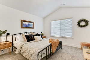 Bedroom with light carpet and vaulted ceiling