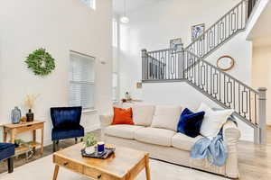 Living room featuring plenty of natural light, a towering ceiling, and light hardwood / wood-style floors