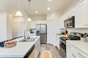 Kitchen with white cabinetry, sink, a kitchen island with sink, and stainless steel appliances