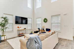 Living room with a towering ceiling and light hardwood / wood-style floors