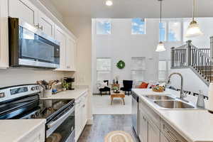 Kitchen with white cabinetry, appliances with stainless steel finishes, sink, and pendant lighting