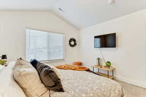 Bedroom with vaulted ceiling and carpet