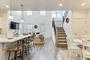 Kitchen with a breakfast bar, sink, white cabinetry, pendant lighting, and hardwood / wood-style floors