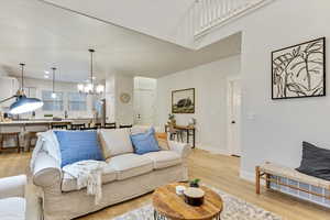 Living room with an inviting chandelier, a high ceiling, and light wood-type flooring