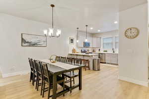 Dining room featuring an inviting chandelier, sink, and light hardwood / wood-style flooring