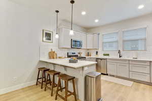 Kitchen featuring decorative light fixtures, sink, a kitchen bar, kitchen peninsula, and stainless steel appliances