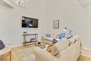 Living room with a towering ceiling and light hardwood / wood-style floors