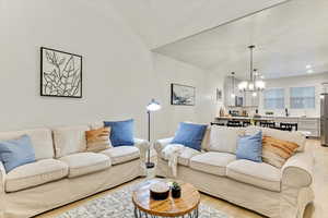 Living room with sink, a chandelier, and light wood-type flooring