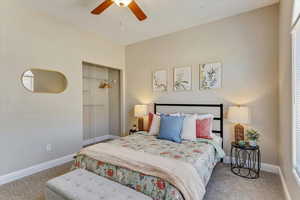 Carpeted bedroom with ceiling fan and a closet