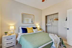 Carpeted bedroom featuring ceiling fan and a closet