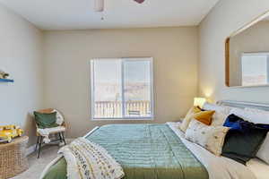 Carpeted bedroom featuring multiple windows and ceiling fan