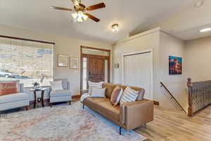 Living room featuring ceiling fan, lofted ceiling, and light hardwood / wood-style flooring