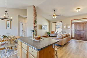 Kitchen with hanging light fixtures, a kitchen island, lofted ceiling, and light hardwood / wood-style flooring