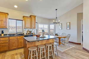 Kitchen featuring sink, hanging light fixtures, a center island, tasteful backsplash, and light hardwood / wood-style floors