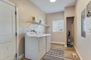 Laundry area featuring washing machine and clothes dryer and light wood-type flooring