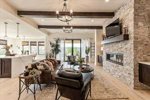 Living room with beamed ceiling, an inviting chandelier, and light hardwood / wood-style floors