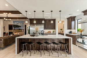 Kitchen with pendant lighting, sink, a breakfast bar area, a large island with sink, and stainless steel appliances