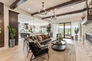 Living room featuring beamed ceiling, sink, light wood-type flooring, and a notable chandelier