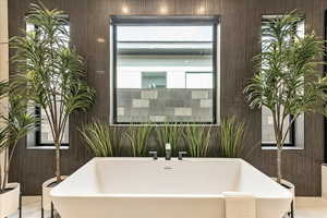 Bathroom featuring sink, a wealth of natural light, and a tub to relax in