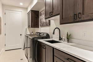 Laundry room featuring cabinets, sink, and washing machine and dryer