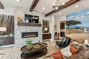 Living room featuring an inviting chandelier, beam ceiling, a fireplace, and light hardwood / wood-style floors