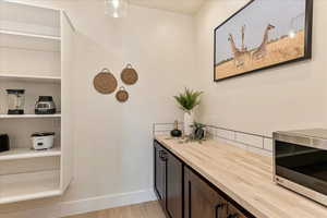 Bar featuring wood counters, light hardwood / wood-style floors, and dark brown cabinets