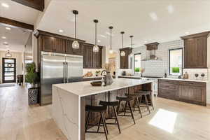 Kitchen with high quality appliances, wall chimney range hood, pendant lighting, and a spacious island