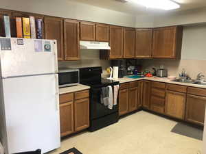 Kitchen featuring black range with electric stovetop, sink, and white fridge