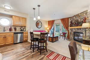 Kitchen with sink, a fireplace, decorative backsplash, decorative light fixtures, and stainless steel dishwasher