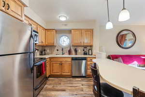 Kitchen featuring pendant lighting, tasteful backsplash, sink, stainless steel appliances, and light hardwood / wood-style flooring